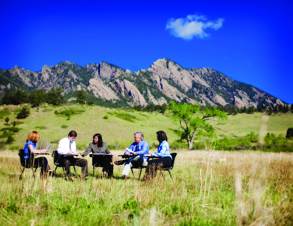Three colleagues discussing notes around a meeting table.